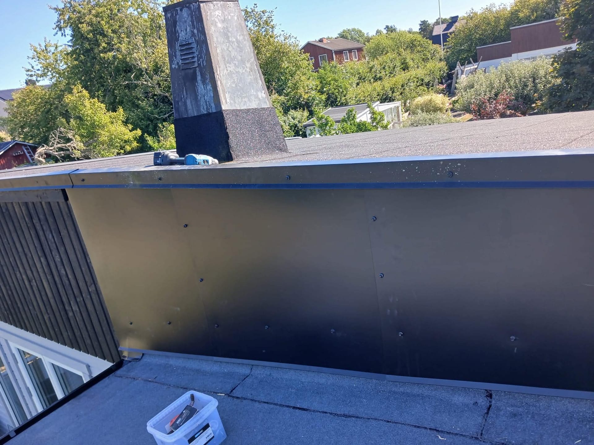 Plåt och papptak kring skorsten på villa